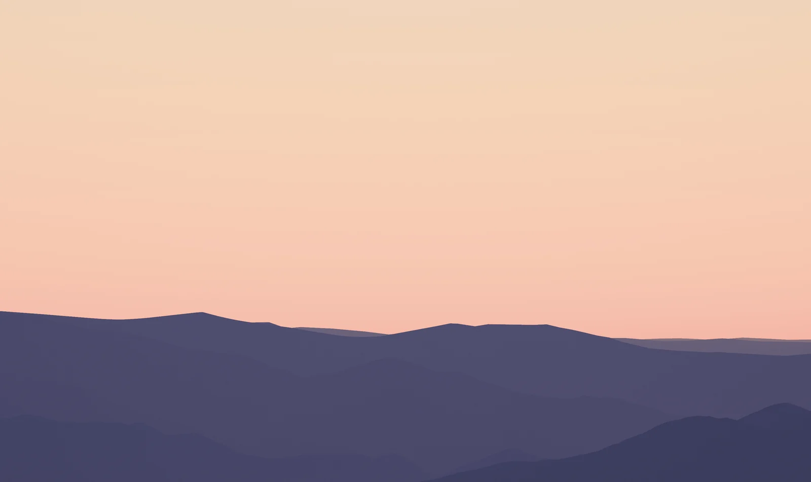 Violet mountain silhouettes beneath a glowing peach and pink sky just after sunset.